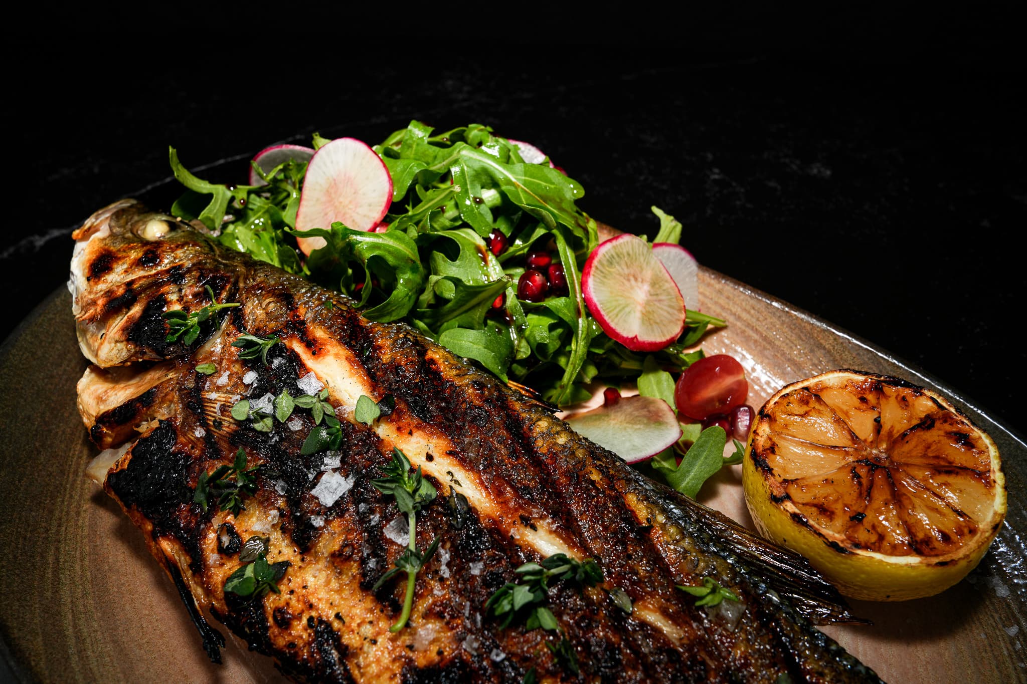 Whole grilled fish with herbs, salad, and dipping sauce from Pera's menu shoot
