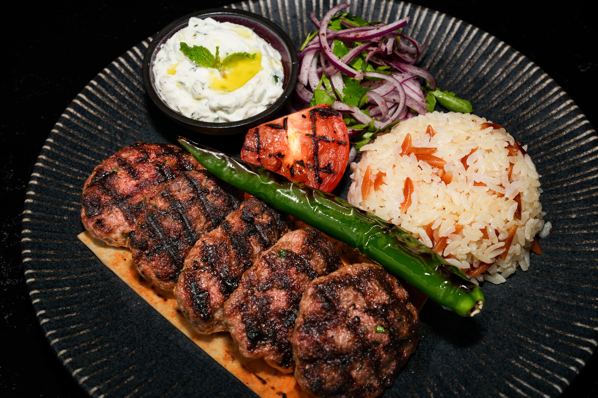 Grilled kebab plate with rice, onions, and yogurt from Pera